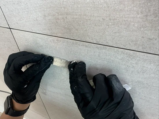 장갑을 낀 작업자가 조색한 에폭시 보수제로 아트월 구멍을 채우는 과정