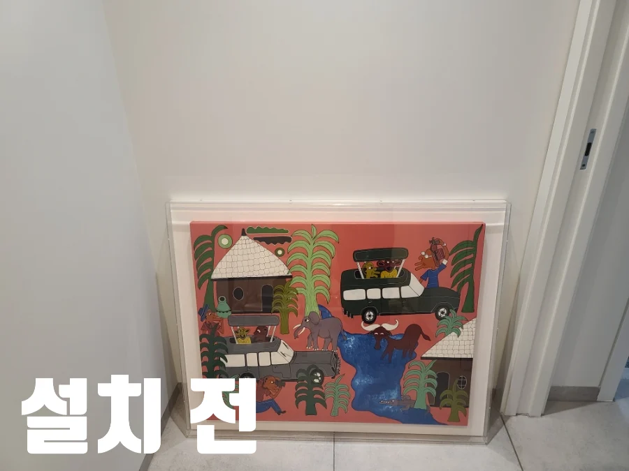 현관 벽 앞에 아크릴 액자를 세워 둔 설치 전 모습