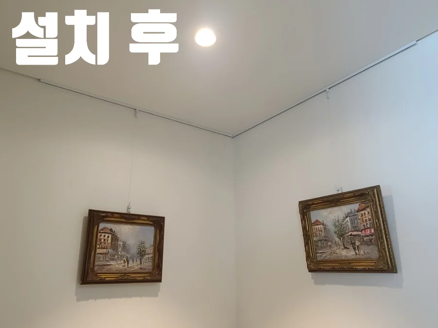 설치 후 문구와 함께 노출형 레일에 클래식 그림 두 점을 건 모습